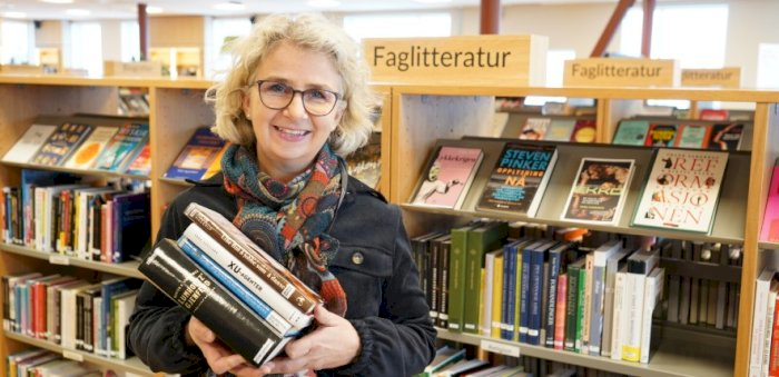 Bilde: Formidler Elisabeth K. Johansen foran bokhylle